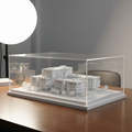 Finished white scale-model diorama under a clear display case on a desk, studio light