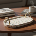 Handmade terrazzo tray with brass handles on a coffee table, warm light