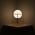 Frosted globe table lamp in a minimalist metal frame glowing warmly on a shelf